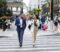 Full length view of male and female associates crossing street side by side, talking and smiling, enjoying break from the office.