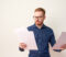 Portrait of young office worker in casual clothing wearing eyeglasses and  concentrating on reading the document on white background