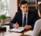 Lawyer discussing and signing documents with a client in a law office, scales of justice on the desk.